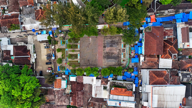 Aerial view of Ciwidey public square surrounded by dense urban housing with red-tiled roofs and blue tarps in Bandung, West Java, Indonesia.