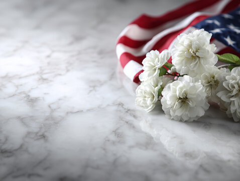Folded American flag and white flowers positioned at the lower edge of a luxurious white marble surface, soft natural window lighting, elegant Martin Luther King Jr. Day tribute concept