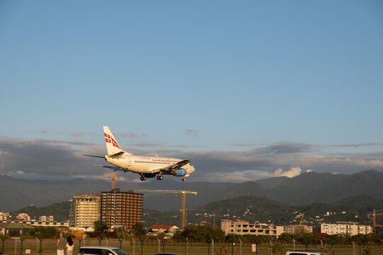 October 2, 2026, Batumi: Georgian Airways passenger plane descending for landing over city buildings against a clear blue sky.