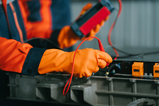 Expert ev repair shop ev car ev mechanic shows focused emotion during high voltage battery maintenance in professional garage work space