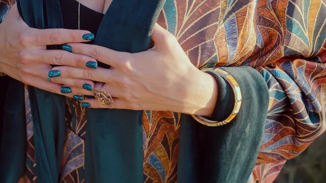 Woman Hands Touching Luxurious Silk Kimono With Elegant Manicure. Boho style jewelry. Turquoise nails, jewelry and colorful patterns create an elegant bohemian fashion and lifestyle scene.