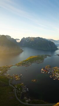 Time lapse of the midnight sun and the ocean, mountains and town of Reine along the amazing coast of Northern Norway. Vertical video.