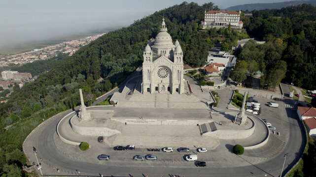 Aerial view of the Sanctuary of the Sacred Heart of Jesus with its stone facade and rose window, surrounded by forest and a paved plaza in Viana do Castelo, Viana do Castelo Dist, Portugal.