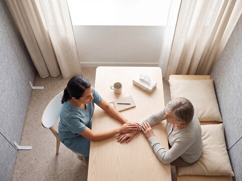 Compassionate nurse comforting a senior patient by holding hands during a therapy session in a clinic