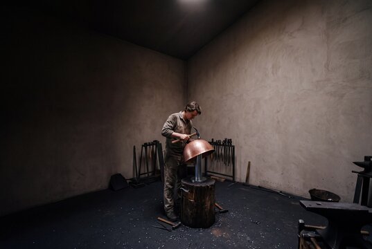 Skilled Artisan Coppersmith Hammering and Shaping a Copper Basin in a Rustic Workshop with Traditional Hand Tools