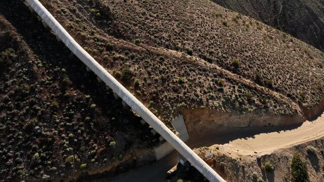 Aerial shot of the Los Angeles Aqueduct as it passes over some low mountains in California. The aqueduct supplies water to Los Angeles and Southern California.