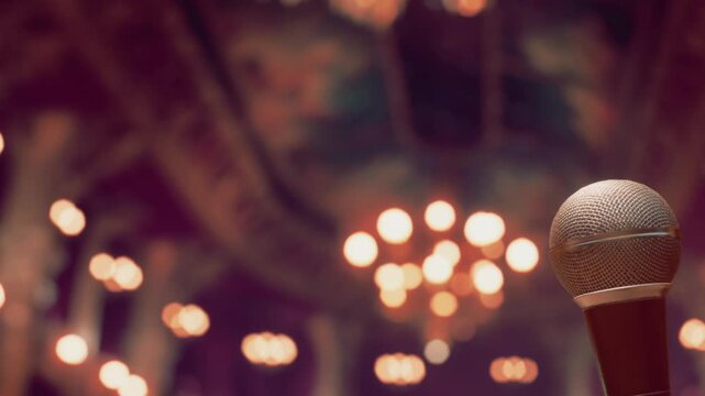 A gleaming microphone stands tall in a lavish venue. Elegant chandeliers illuminate the surroundings, hinting at an exciting event or concert approaching.