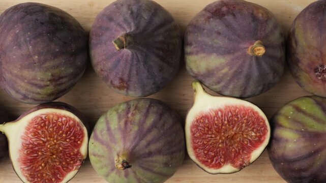 Fresh purple figs whole and sliced on a wooden board