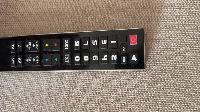 Person operating television remote control on sofa