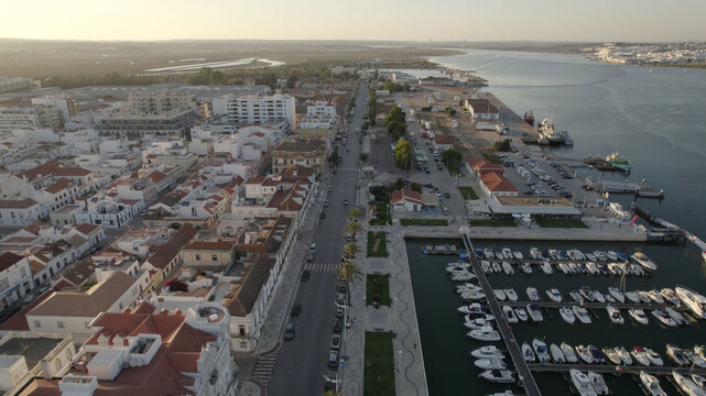 Aerial view of Vila Real de Santo Antonio marina with boats docked along the river, surrounded by white buildings and palm-lined streets in Vila Real de Santo Antonio, Faro District, Portugal.