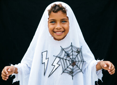 Ni&ntilde;o Feliz Disfrazado de Fantasma de Halloween con Telara&ntilde;a y Rayos / Happy Boy Dressed in Halloween Ghost Costume with Spider Web and Lightning Bolts
