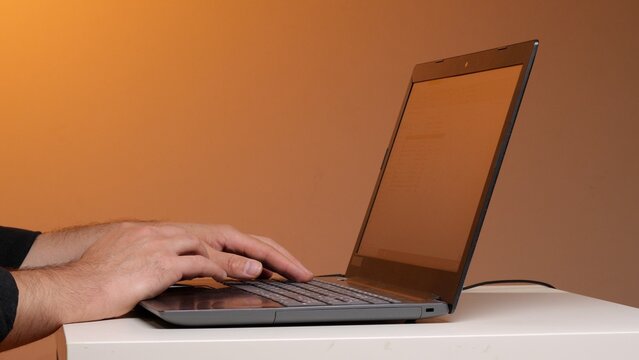 Hands typing on a laptop keyboard in a modern workspace, illustrating programming, remote work, data entry and digital productivity in a professional home or office setting