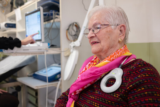 Elderly woman with a medical device checking a heart pacemaker during a cardiology visit at hospital