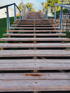 Escalier en bois dans le parc avec des rampes en m&eacute;tal. 
Gros plan sur des marches en bois.	