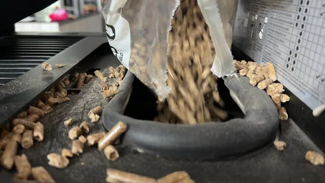 Pouring wood pellets into hopper of pellet grill close up