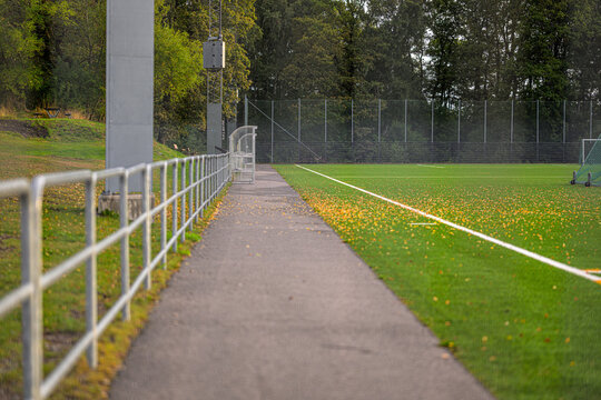 Empty sports facility walkway beside artificial football pitch.