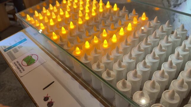 Person activating electronic votive candle. hand lighting votive candle on religious candle stand