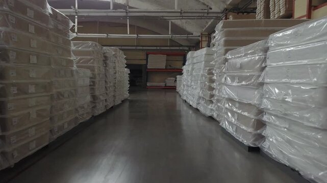 Drone flies low forward through mattress rows in Klin