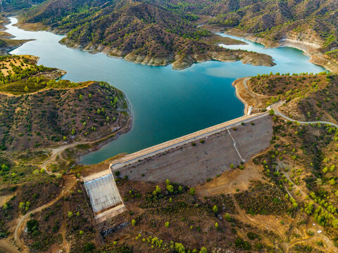 Aerial view of Dipotamos Reservoir and its dam structure surrounded by rugged hills and landscape in Dimos Lefkaron, Larnaca, Cyprus.