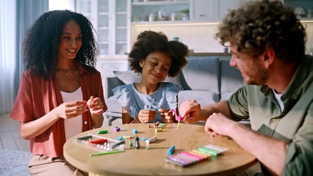 Child sculpting colorful clay figures parents. Multiracial family home table.