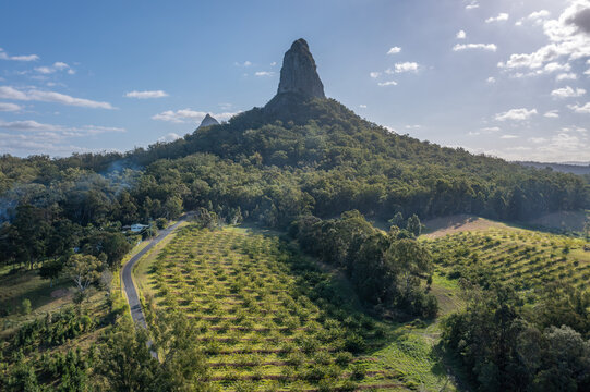Aerial view of Mount Coonowrin rising above the lush forests and orchards of the Glass House Mountains, Queensland, Australia.