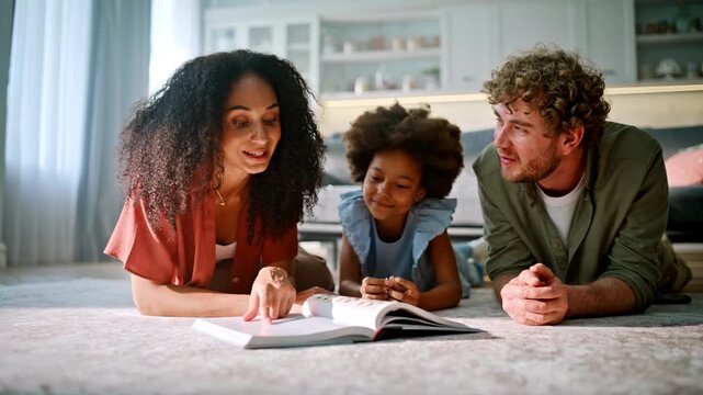 Young mom teaching daughter book living room floor. Multiracial family home.