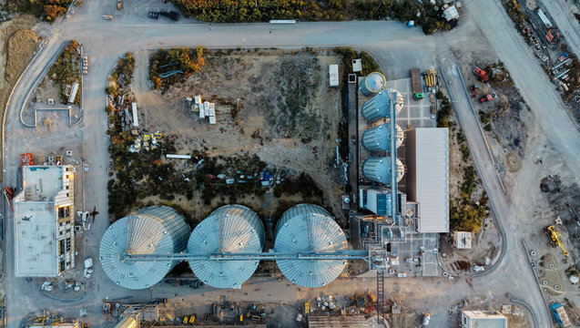 Aerial view of the construction of a distillery featuring large metal silos and industrial buildings surrounded by construction site infrastructure in Kovacica, Vojvodina, Serbia.