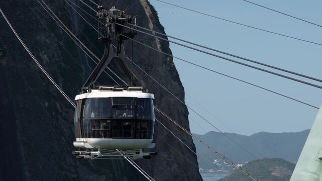 Cable car descending from Sugarloaf Mountain toward Morro da Urca on a sunny day, Rio de Janeiro, Brazil.