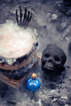 Skeletal claws rise from a cauldron vessel.