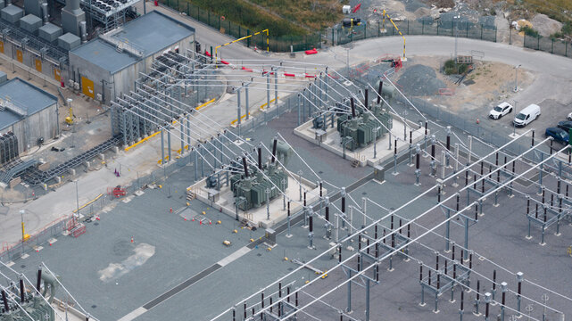 Aerial view of the Thurrock Flexible Generation Substation featuring electrical transformers and power infrastructure on a gravel site in Tilbury, England, United Kingdom.