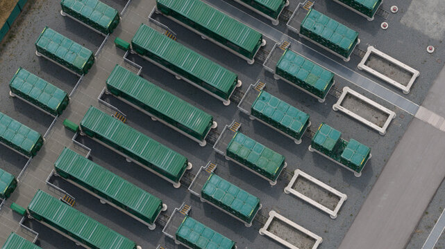 Aerial view of Thurrock Flexible Generation Substation featuring rows of green battery storage containers arranged on a paved site in Tilbury, England, United Kingdom.