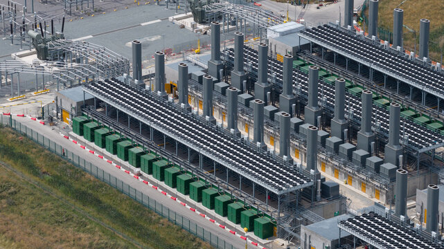 Aerial view of the Thurrock Flexible Generation Substation featuring rows of industrial generators, cooling units, and electrical infrastructure in Tilbury, England, United Kingdom.