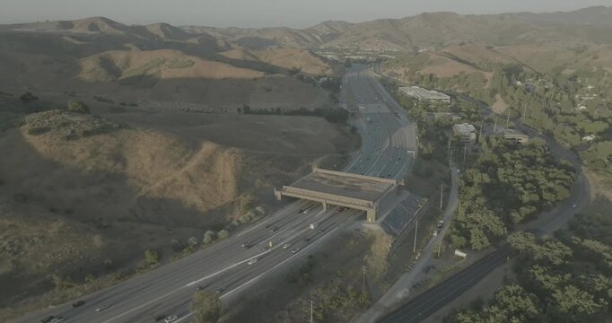 Drone shot over busy highway and overpass in backlit hazy hills
