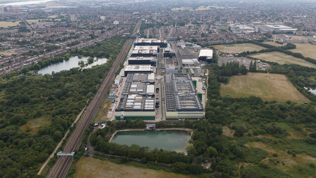 Aerial view of the NTT LON1B Data Centre complex, featuring large industrial buildings, cooling systems, and surrounding green space near a railway line in Dagenham, England, United Kingdom.