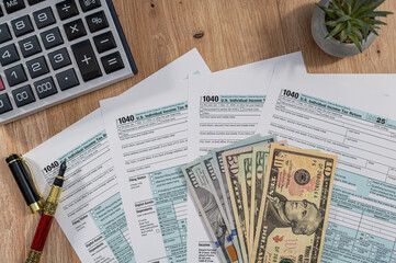 Obraz premium US Individual Income Tax Return Form 1040 with USD Dollar Bills and Calculator for Tax Concept