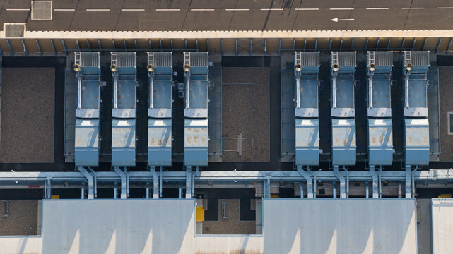 Aerial view of the Google Data Centre in Waltham Cross, featuring rows of industrial HVAC cooling units on the rooftop, adjacent to a paved road, in Cheshunt, England, United Kingdom.