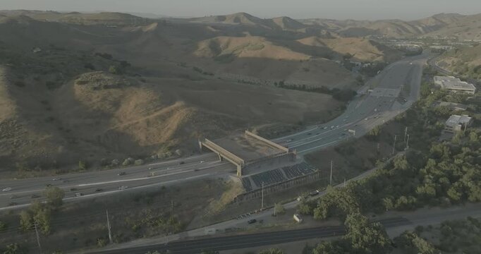 Aerial view of highway lanes passing under bridge among dry hills