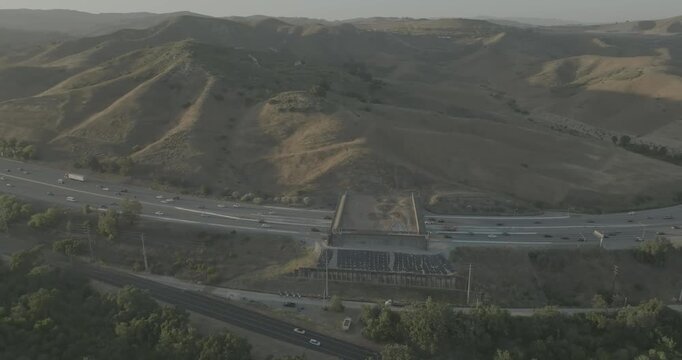 Drone shot over busy highway and overpass in backlit hazy hills