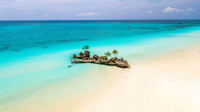 Aerial view of Willy's Rock, a volcanic formation with a statue of the Virgin Mary, surrounded by turquoise waters and white sand beach in Malay, Western Visayas, Philippines.