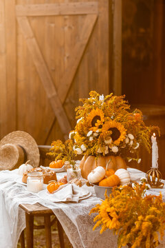 Cozy autumn table decoration for a thanksgiving party outdoors. Centrepiece with sunflowers, candles, pumpkins as decor. Elegant wedding fall arrangement, beautiful setting for a romantic lunch.