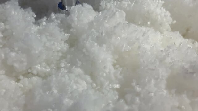 White synthetic fiber stuffing mixing inside special glass display unit showing fiberfill used for kids toys, fluffy fiber stuffing showcase allowing customers see what children's toys filling made of