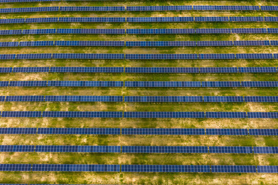 Aerial view of rows of solar panels installed in a large grassy field in Latvia.