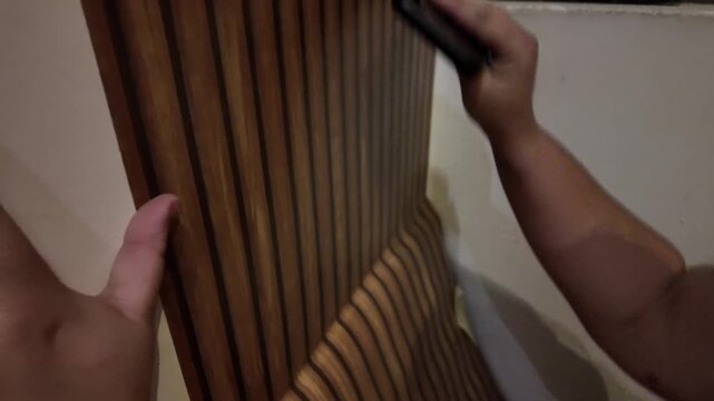 Hand smooths wooden panel with gentle pressure