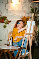 Woman artist painting on canvas easel for creative hobby © Jelena