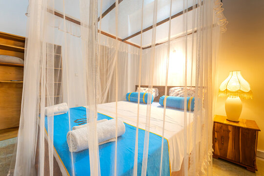 Minimalist villa bedroom interior with comfortable bed and mosquito net canopy
