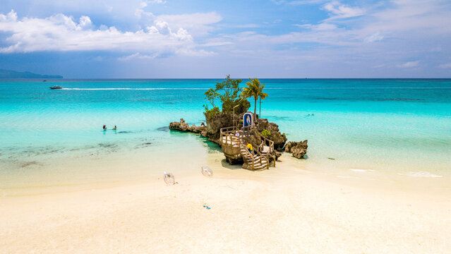 Aerial view of Willy's Rock on the white sand beach of Boracay Island with turquoise water and a blue sky in Malay, Western Visayas, Philippines.
