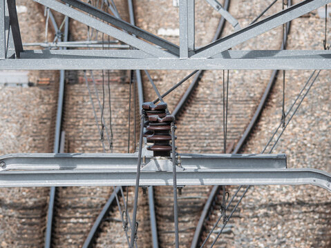 Messenger wire suspension assembly securing the messenger wire to the overhead contact line bracket of the catenary system above a railway station turnout