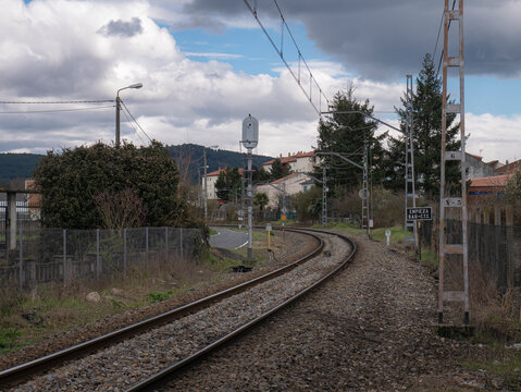 Train track on a curved path under the catenary wires and a sign on the side of the track indicating "start single track automatic blocking (BAU) and centralized traffic control (CTC)"