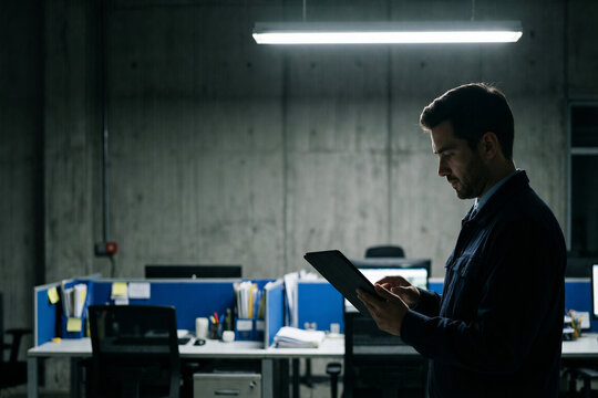 Businessman using a tablet in an industrial office at night