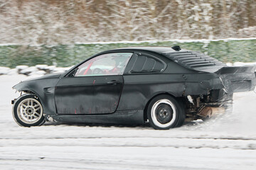 Sleek dark sports car unleashing intense flames during snowy performance © diczman